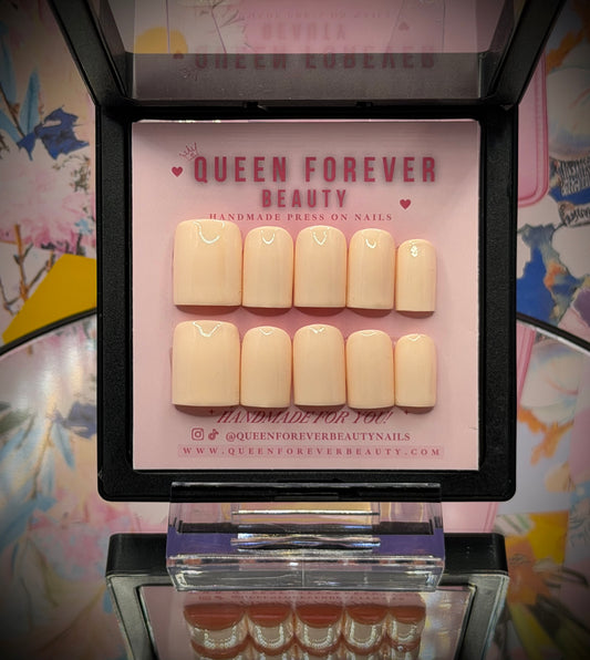 A set of 10 press-on nails in a warm nude beige color, displayed in an open black case with a pink insert card branded 'QUEEN FOREVER BEAUTY'.